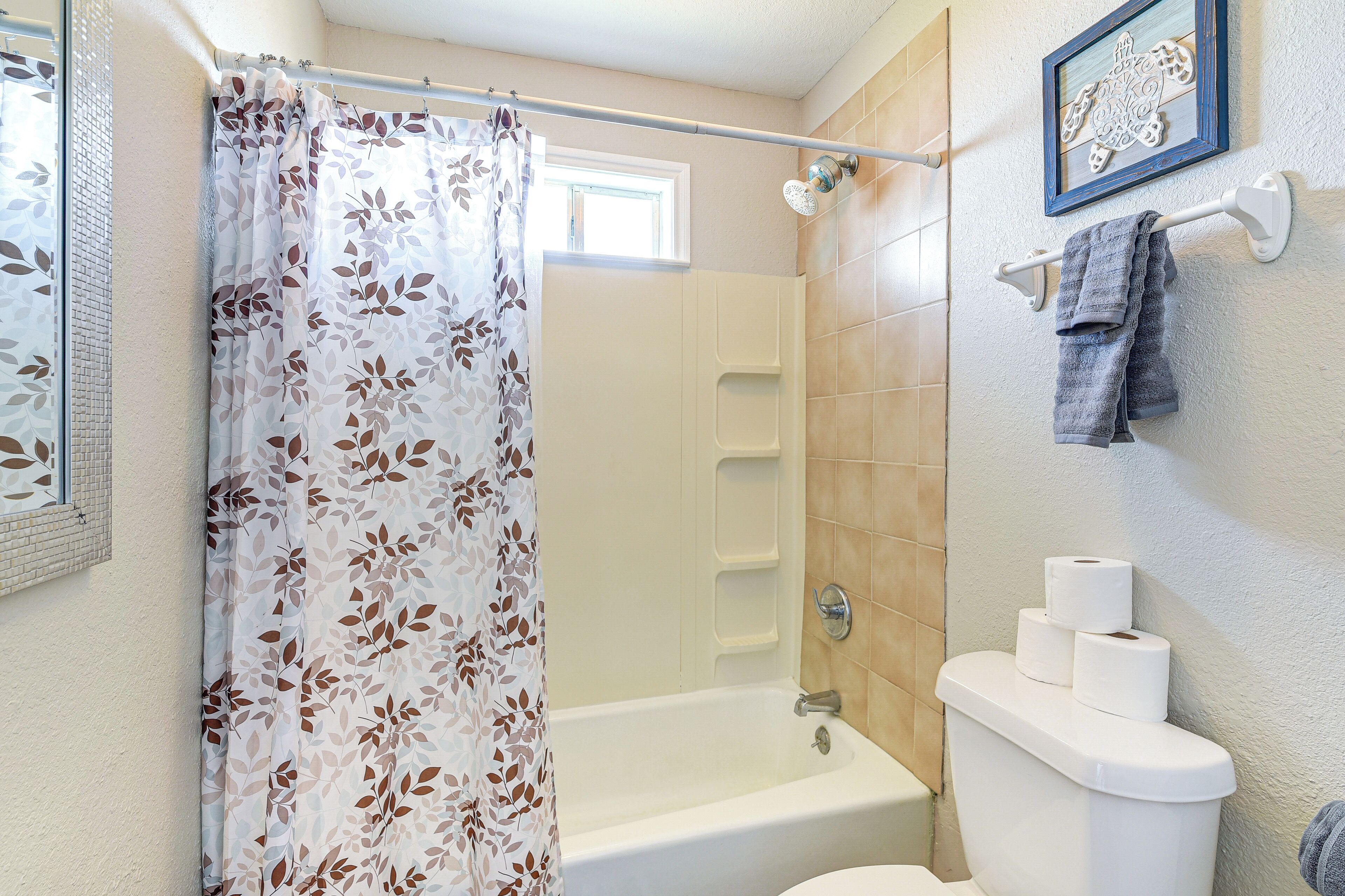 A bathroom with a shower curtain, a bathtub, a toilet, and a towel rack.