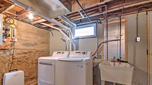 A laundry room with two front-loading washing machines, a dryer, and a sink with a window above. - Cozy Missouri Retreat w/ Pool, Pond & Fire Pit! (Berger)