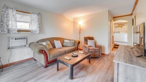 A living room with a sofa, armchair, coffee table, and a wooden dining table. - Table Rock Lake Cabin w/ Deck & Bar! (Shell Knob)