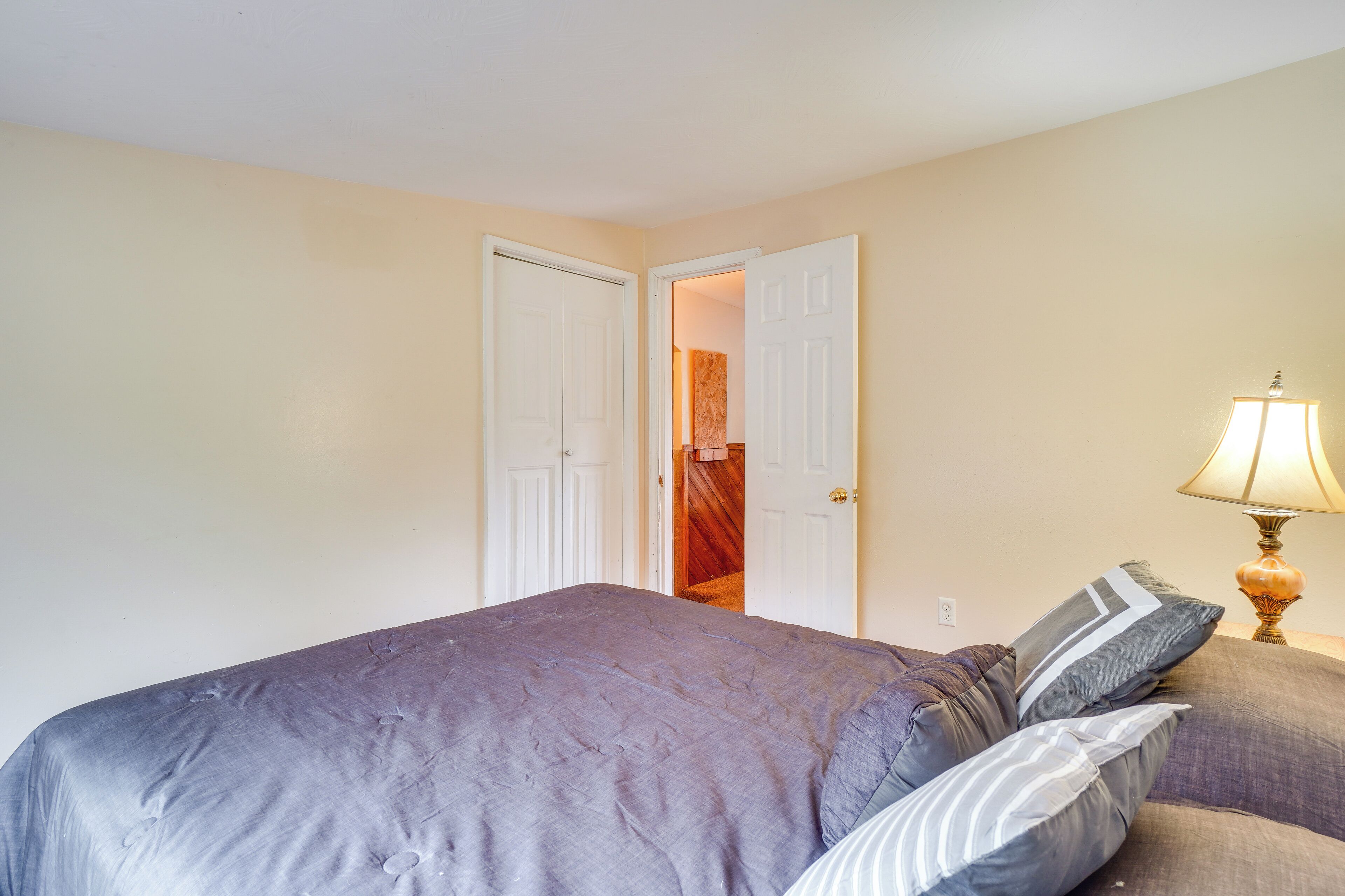 A bedroom with a bed, pillows, a nightstand, and a lamp.