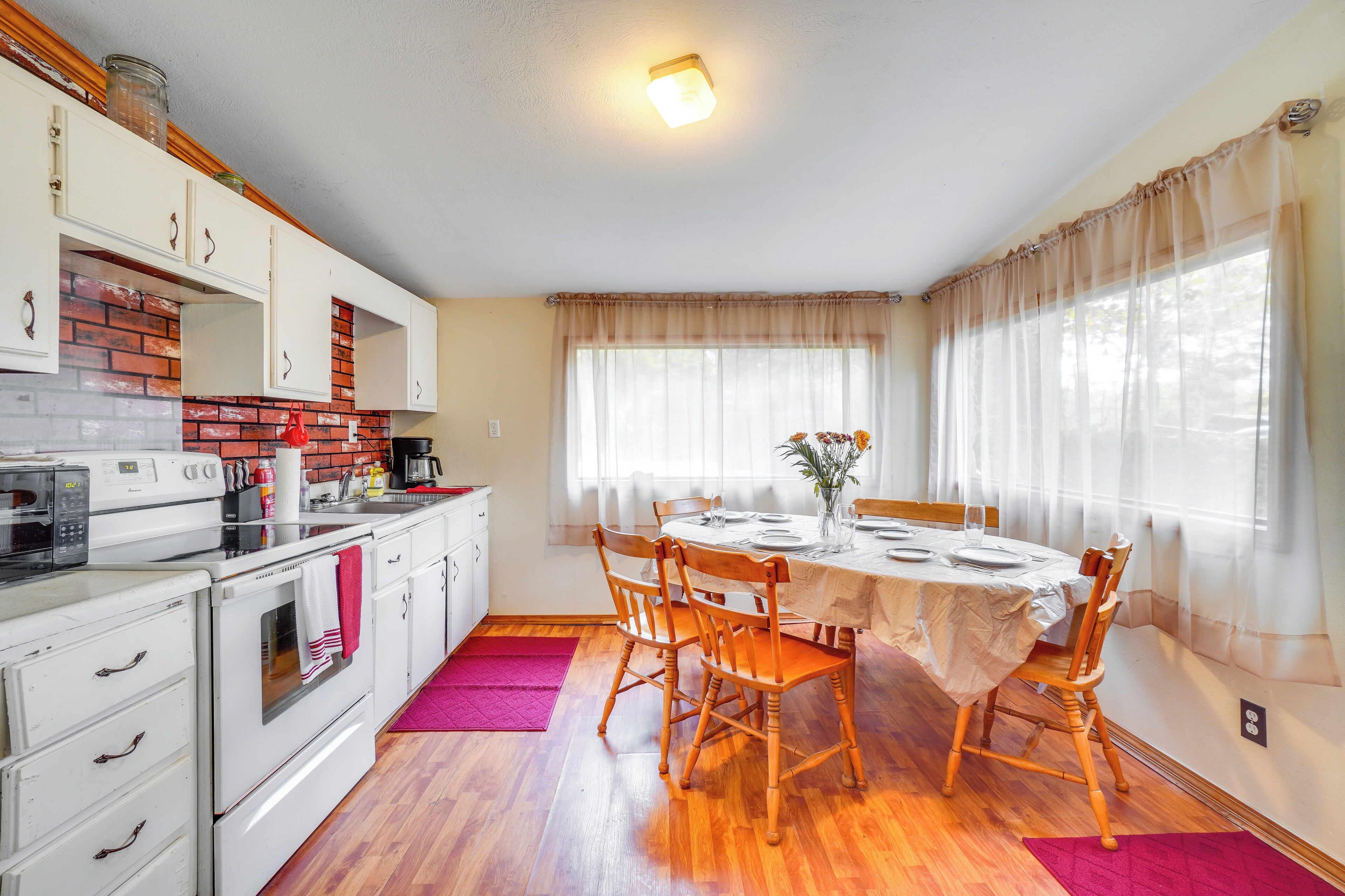 A kitchen with white cabinets, a microwave, and a stove. There is a dining table with chairs and a vase with flowers.