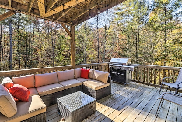 A covered outdoor deck with a wooden bench, a wicker sofa with cushions, a grill, and a view of a forest. - 'the Toasted Marshmallow' Mt Jackson Retreat! (Basye)