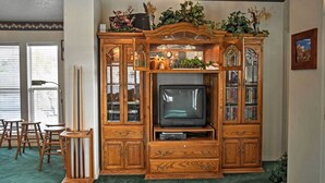 A wooden entertainment center with a television, glass cabinets, and decorative plants. - Sunny La Verkin Studio - 20 Mi to Zion Nat'l Park! (La Verkin)