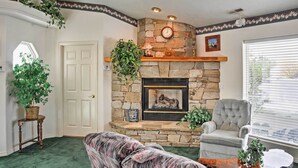 A living room with a stone fireplace, a comfortable armchair, and a large plant. - Sunny La Verkin Studio - 20 Mi to Zion Nat'l Park! (La Verkin)