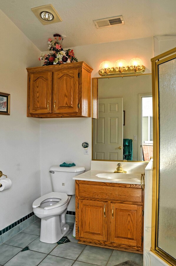 A bathroom with wooden cabinets, a toilet, a sink, and a mirror. - Sunny La Verkin Studio - 20 Mi to Zion Nat'l Park! (La Verkin)