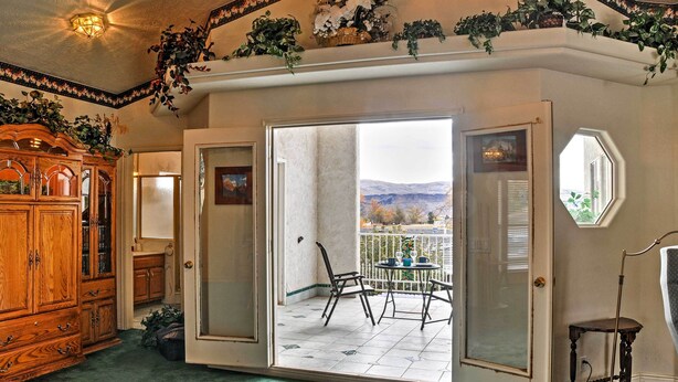 A room with a wooden cabinet, a sliding glass door leading to a balcony with a table and chairs, and a small table with a lamp. - Sunny La Verkin Studio - 20 Mi to Zion Nat'l Park! (La Verkin)
