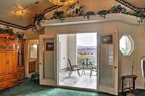 A room with a wooden cabinet, a sliding glass door leading to a balcony with a table and chairs, and a small table with a lamp. - Sunny La Verkin Studio - 20 Mi to Zion Nat'l Park! (La Verkin)