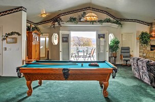 Una mesa de billar en una habitación con vistas al exterior, una silla y un sofá.