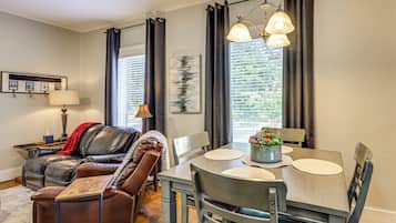 A modern dining area with a table set for four, leather seating, and a view through large windows.