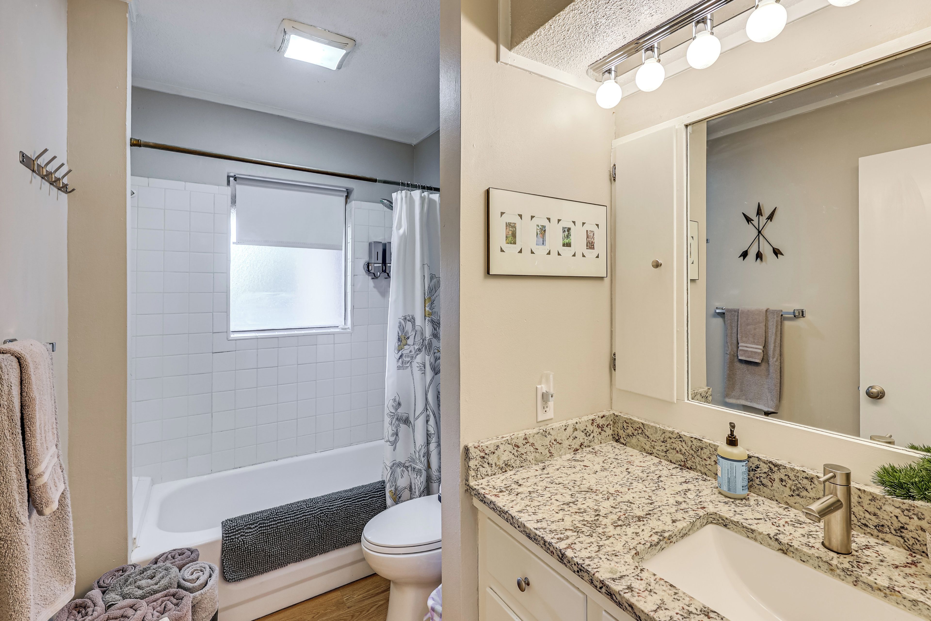 A bathroom with a bathtub, toilet, and a sink with a mirror.