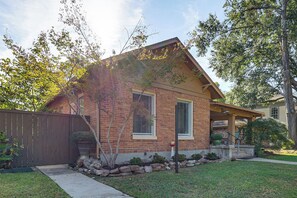 A two-story house with a brick facade, a covered porch, and a well-maintained lawn. - Texarkana Pet-friendly Pad w/ Fenced Backyard (Texarkana)