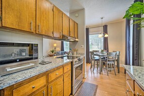 Una cocina moderna con armarios de madera, electrodomésticos de acero inoxidable y una zona de comedor con mesa y sillas.