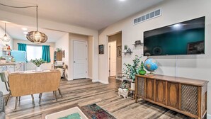 Un salon moderne avec une table à manger en bois, un téléviseur fixé au mur et un globe terrestre posé sur un meuble.