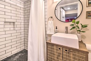 A modern bathroom with a shower area, a sink, and a mirror.