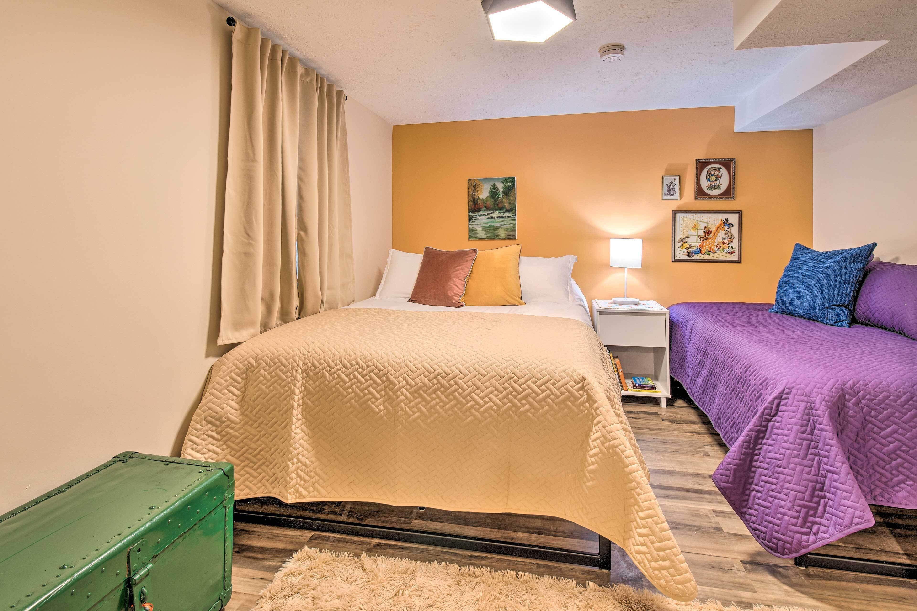 A hotel room with a bed, a nightstand, a lamp, and a green suitcase.