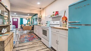 Une cuisine avec des armoires blanches, un réfrigérateur de couleur turquoise et un plan de travail en bois.