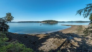 Ein klarer Blick auf einen See mit einem Sandstrand und einer kleinen Insel in der Ferne.