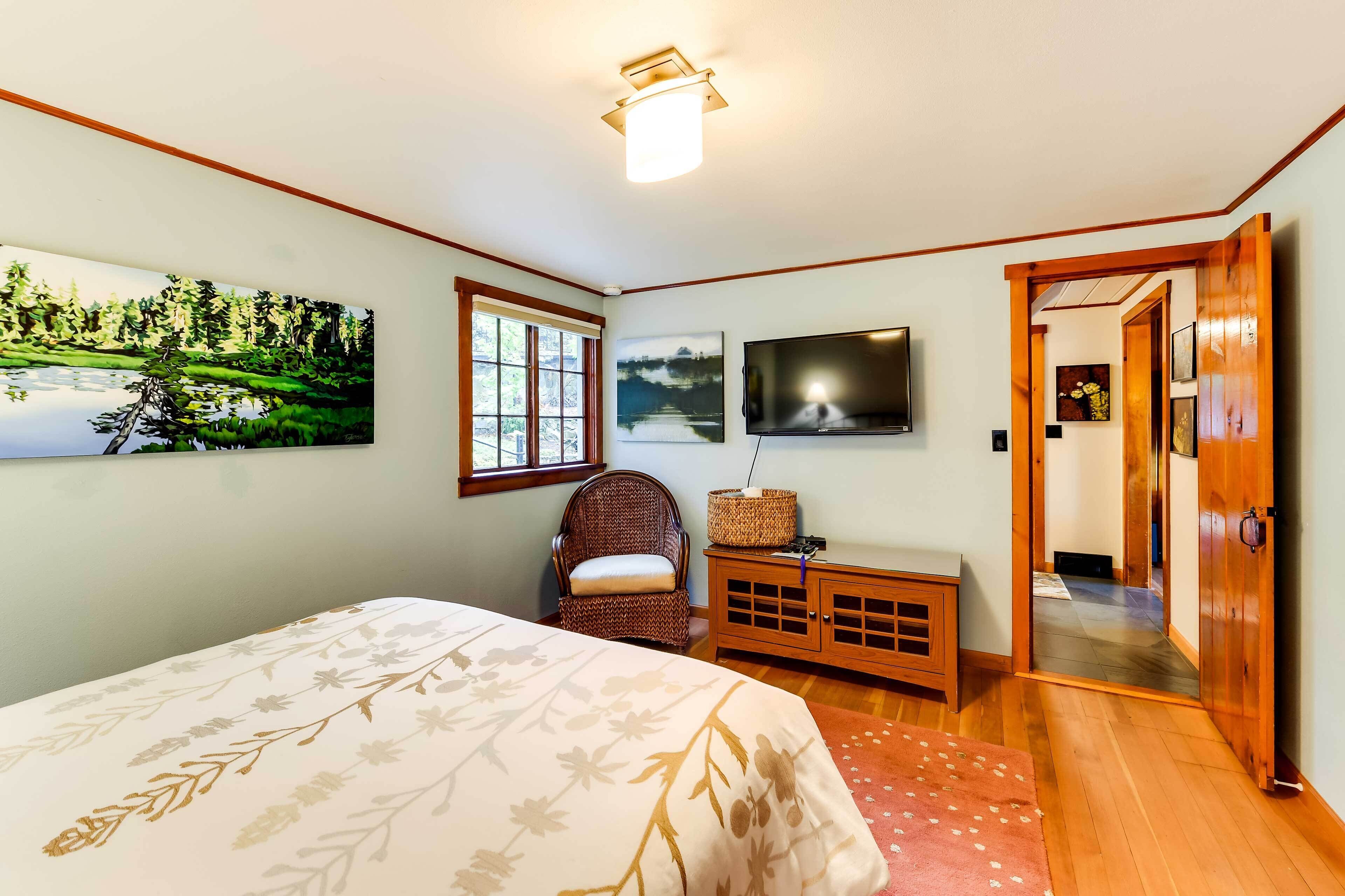A bedroom with a bed, a chair, a TV, and a painting on the wall.