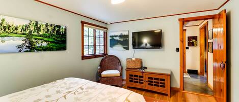 A bedroom with a bed, a chair, a TV, and a painting on the wall.