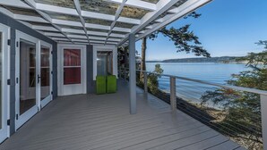 Eine überdachte Terrasse mit Seeblick, ausgestattet mit einer Glasdecke und einem Geländer.