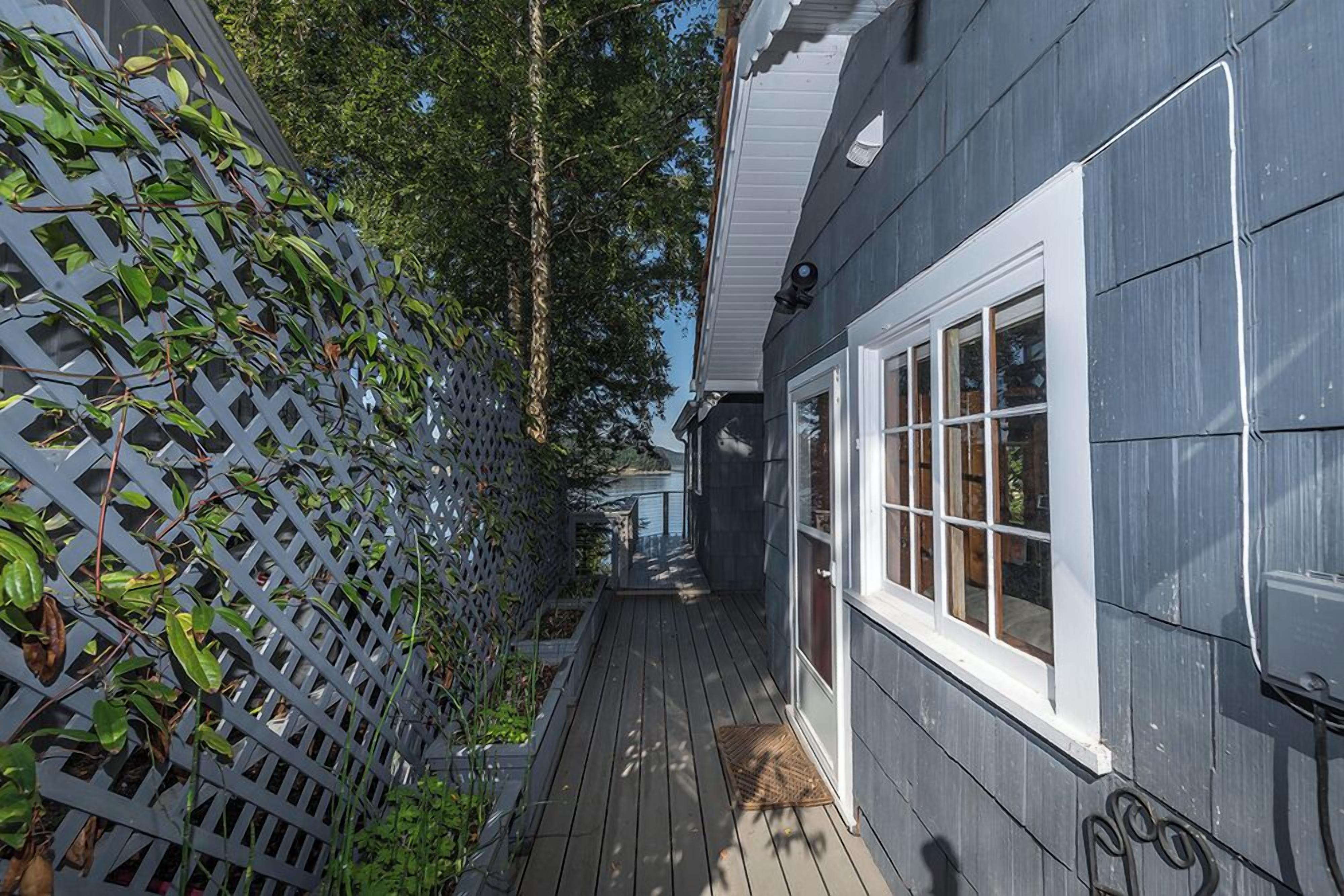 A wooden deck with a white lattice fence and a gray building with windows.