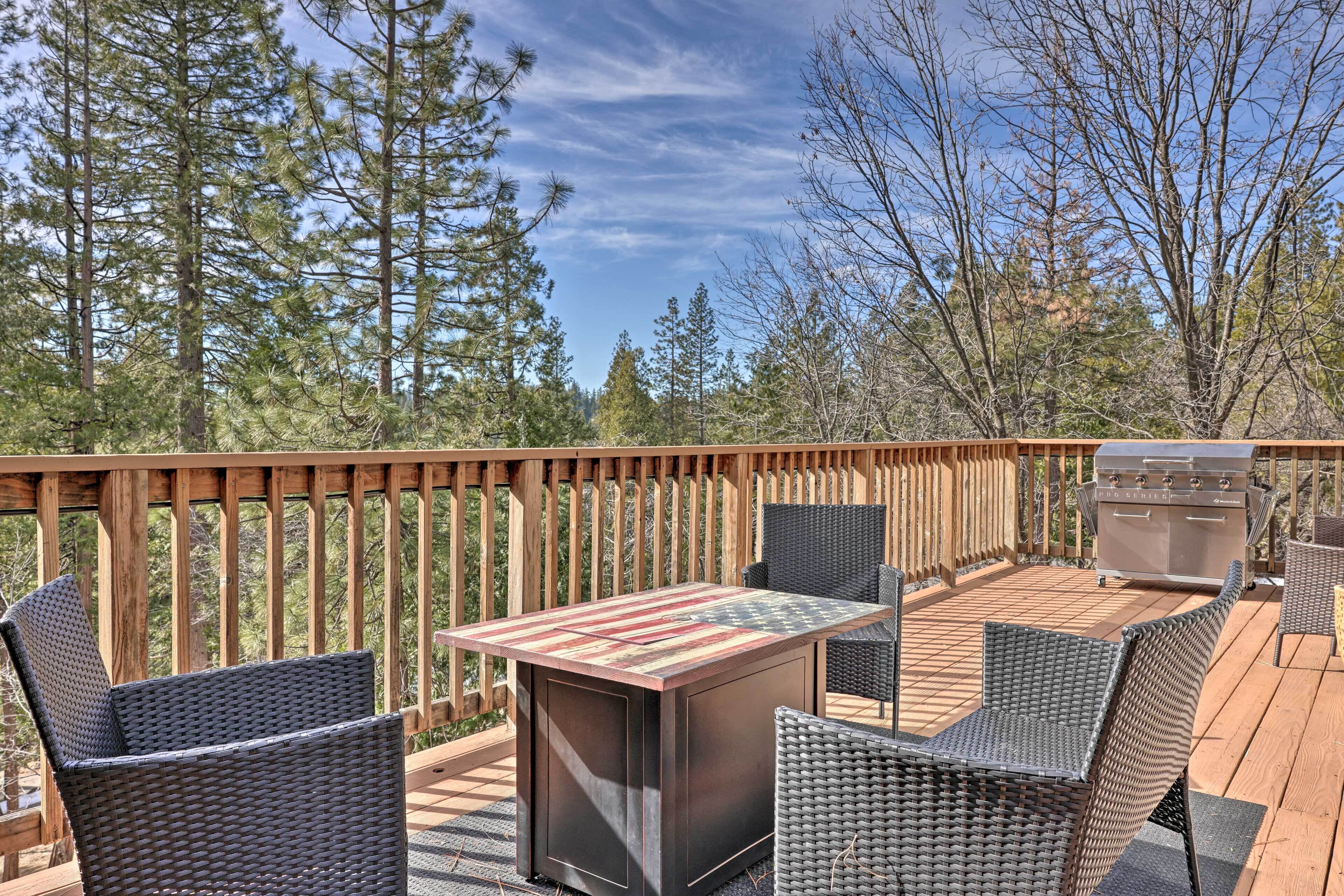 Une terrasse extérieure avec un barbecue, des chaises en osier et une table recouverte d’une nappe à rayures.