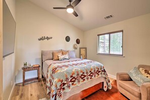A bedroom with a bed, a small bedside table, a ceiling fan, a window with blinds, and a wall-mounted decoration. - Near Hiking + Wineries: Arnold Cabin w/ Deck! (Arnold)