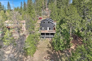 A two-story cabin with a deck, surrounded by dense forest. - Near Hiking + Wineries: Arnold Cabin w/ Deck! (Arnold)