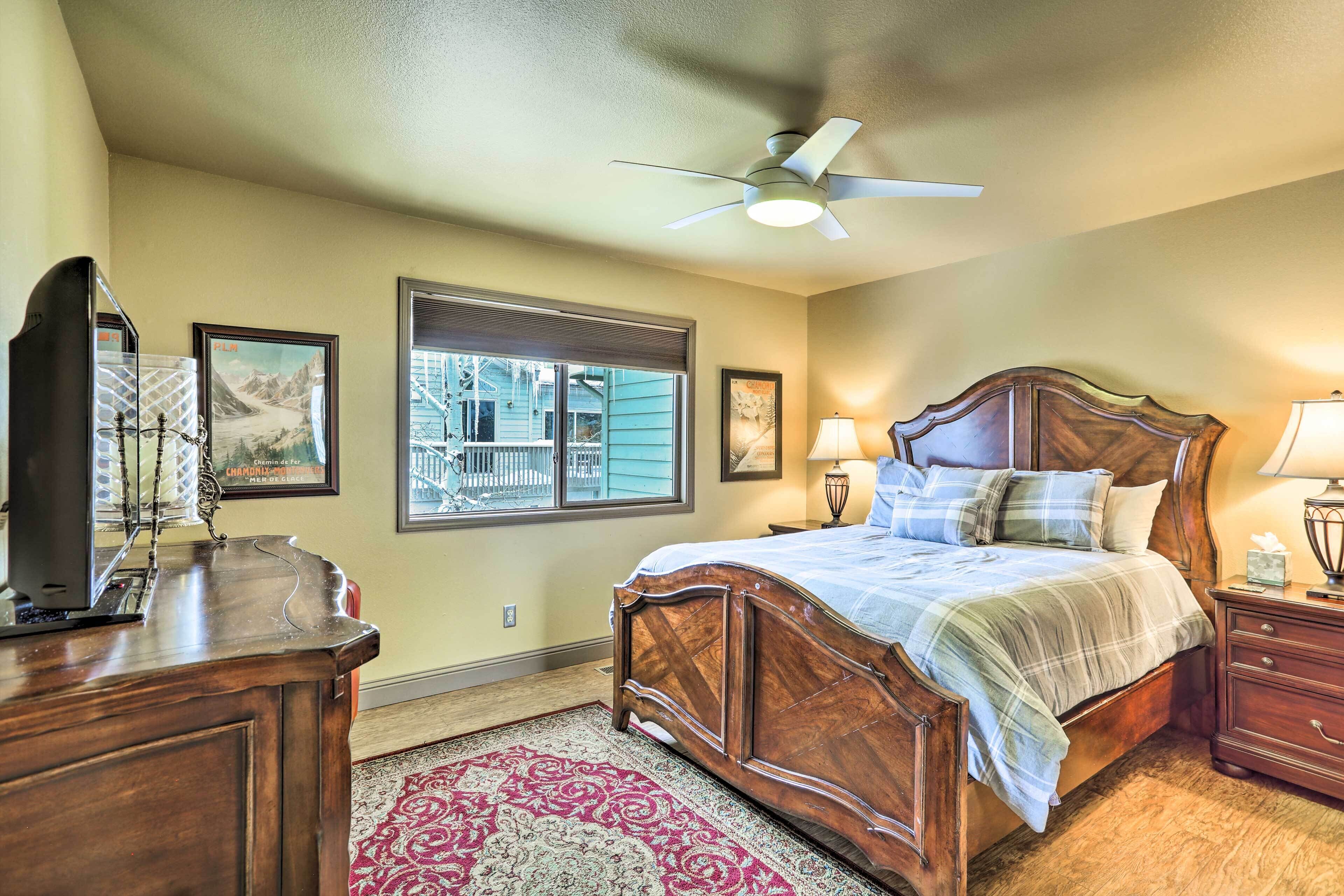 A bedroom with a wooden bed, a desk, and a ceiling fan.