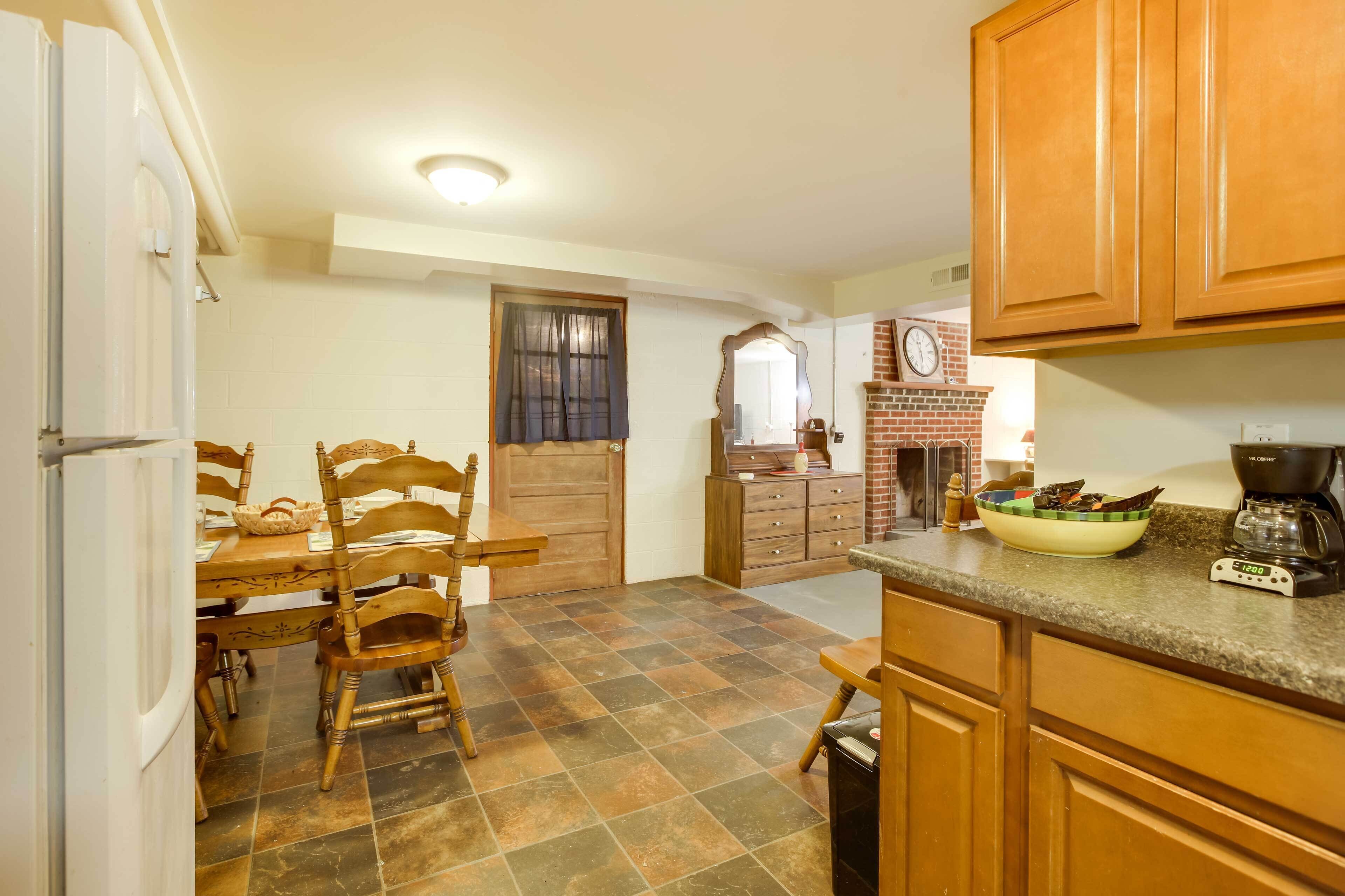A kitchen with wooden cabinets, a tiled floor, a dining table with chairs, and a coffee maker.