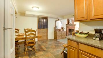 A kitchen with wooden cabinets, a tiled floor, a dining table with chairs, and a coffee maker.