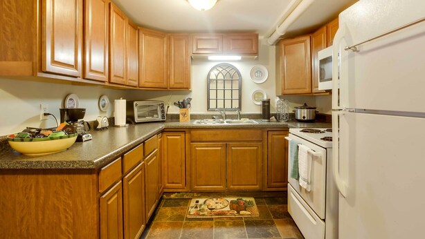 A kitchen with wooden cabinets, a microwave, a stove, and a sink. - Lexington Apt Rental Near VA Military Institute! (Lexington)