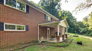A two-story brick house with a covered patio and a small garden. - Lexington Apt Rental Near VA Military Institute! (Lexington)