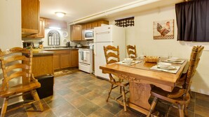 A kitchen with wooden cabinets, a dining table with chairs, a refrigerator, and a microwave. - Lexington Apt Rental Near VA Military Institute! (Lexington)