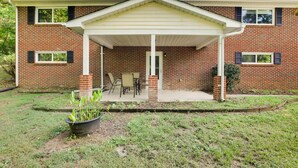A two-story brick house with a covered patio and a small garden area. - Lexington Apt Rental Near VA Military Institute! (Lexington)