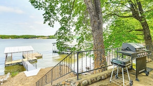 A lakeside deck with a grill and a covered seating area. - Beach + Dock! Lakefront Ozarks A-frame Retreat (Linn Creek)