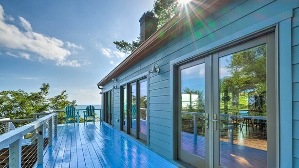 Eine überdachte Terrasse mit blauem Holzboden, großen Schiebeglasfenstern und Gartenmöbeln.