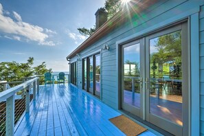 A covered deck with a blue wooden floor, large sliding glass doors, and outdoor seating. - Tranquil Port Republic Home w/ Water Views! (Port Republic)