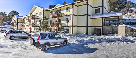 A multi-story hotel with balconies, a parking area, and snow-covered surroundings.