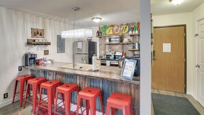 A kitchen with a bar area, bar stools, and a wooden door. - Walkable Lead Condo: 5 Mi to Terry Peak Ski Area! (Lead)