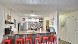 Una cocina con barra, taburetes rojos y diversos electrodomésticos.