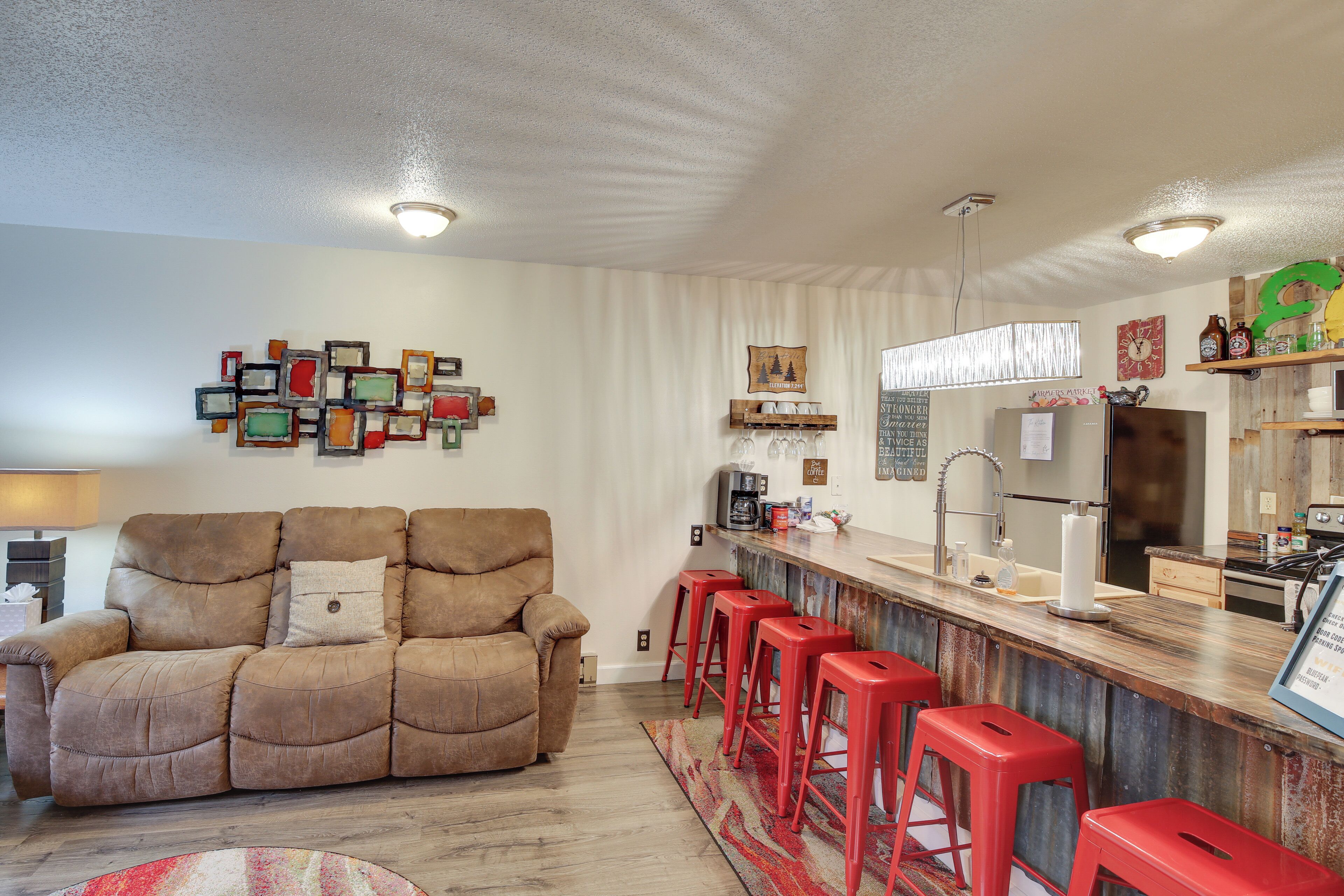 Une cuisine moderne avec un coin bar, un tabouret de bar rouge et un canapé beige.