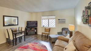 Una sala de estar con televisión, asientos y una ventana.