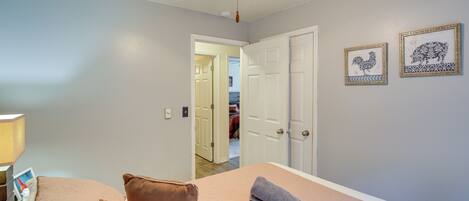A bedroom with a bed, pillows, a ceiling fan, and two framed pictures on the wall.