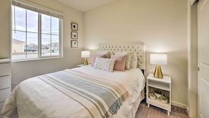 Une chambre avec un grand lit, une table de chevet avec une lampe, une fenêtre avec des stores et une vue sur l’extérieur.