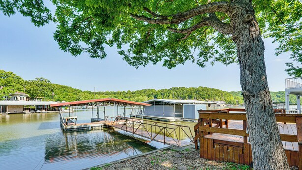Une jetée au bord du lac avec un bateau, une terrasse en bois et un bâtiment avec un toit rouge.