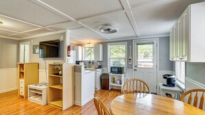 Une cuisine compacte avec des meubles blancs, une table à manger et un petit îlot central équipé d’un four à micro-ondes.