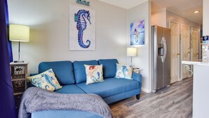 Ein Wohnzimmer mit einem blauen Sofa, einem Bild von einem Seepferdchen und einem Kühlschrank.