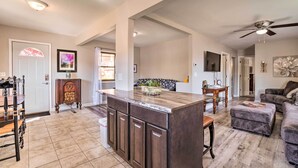 A spacious living area with a large wooden island, a dining table, and a sofa. - Rockaway Beach House w/ Fire Pit & River View! (Rockaway Beach)