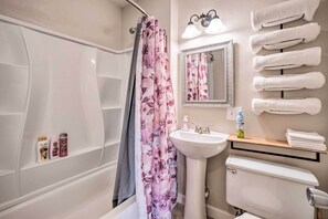 Ein Badezimmer mit Badewanne, Duschvorhang, Waschbecken, Spiegel und Handtuchhalter.